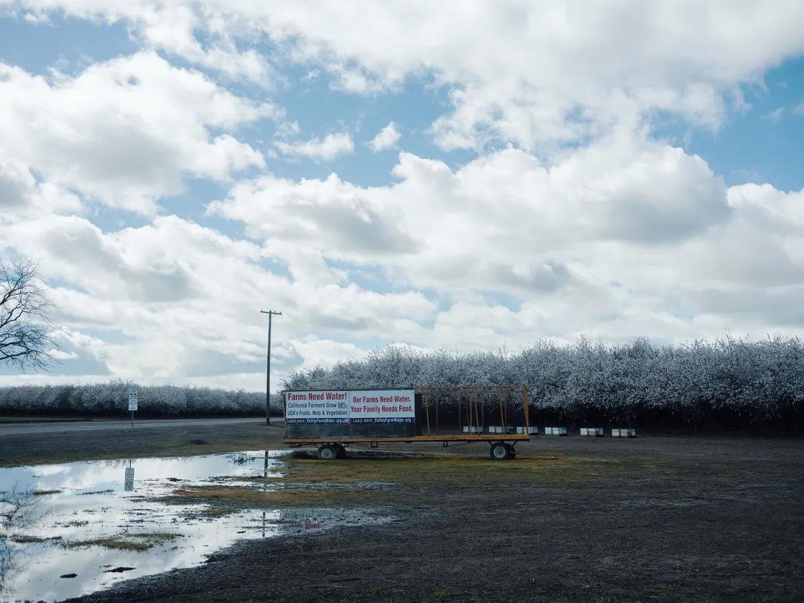 A flooded field with a sign that says farms need water