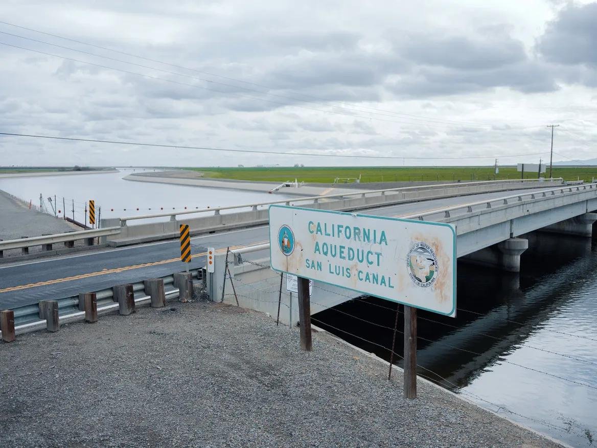 Water cuts through a field with a bridge over it