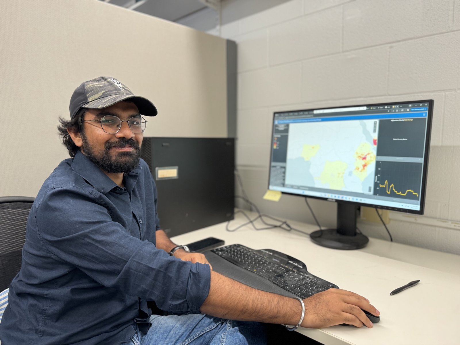 A man in a baseball hat sits in front of a computer monitor showing spacial data