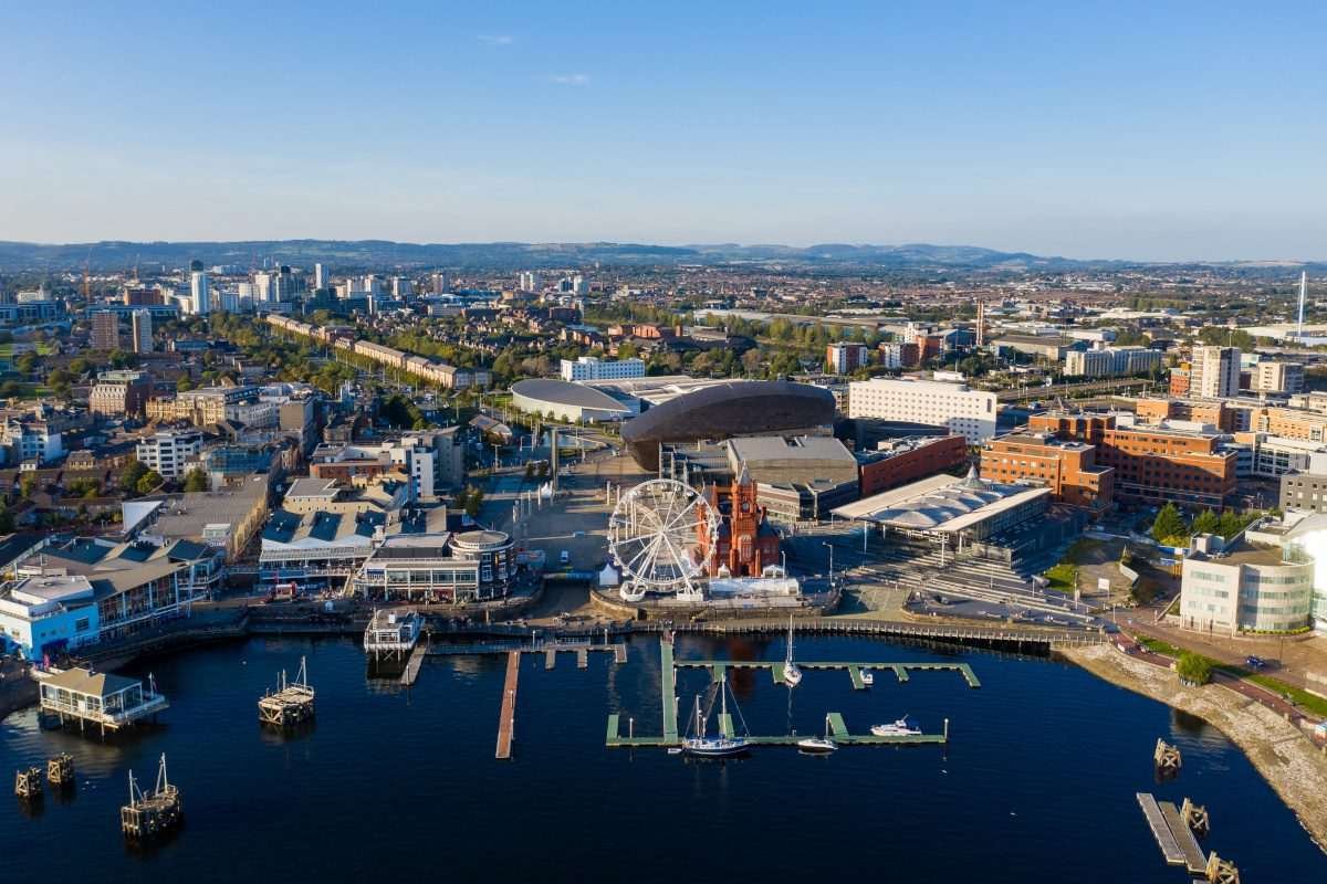 Aerial view of cityscape with foreground region comprising marina area, as if on a river, and other buildings including a big wheel