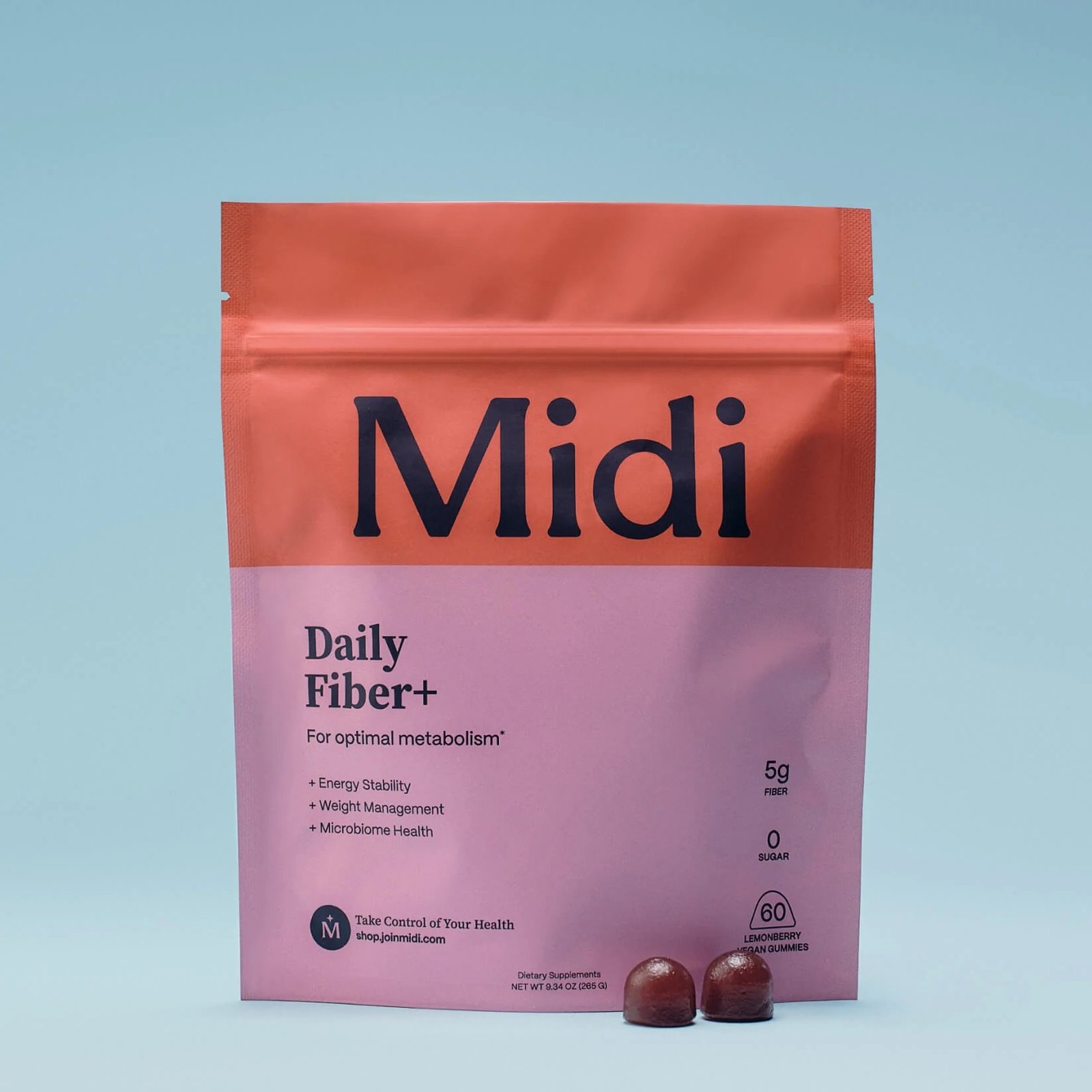 A pink and orange resealable bag labeled "Midi Daily Fiber+" stands upright with two gummy fiber supplements for women placed in front of it on a blue surface.
