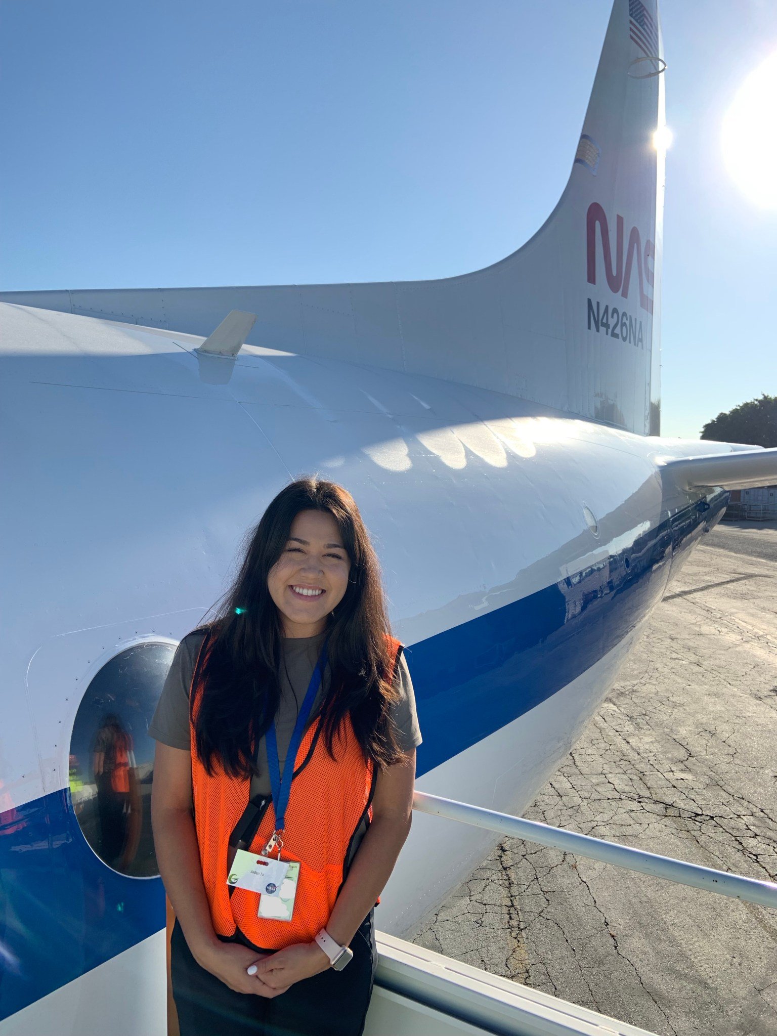Image of NASA Ames scientist Jaden Ta wearing a safety jacket while standing in front of a NASA aircraft.