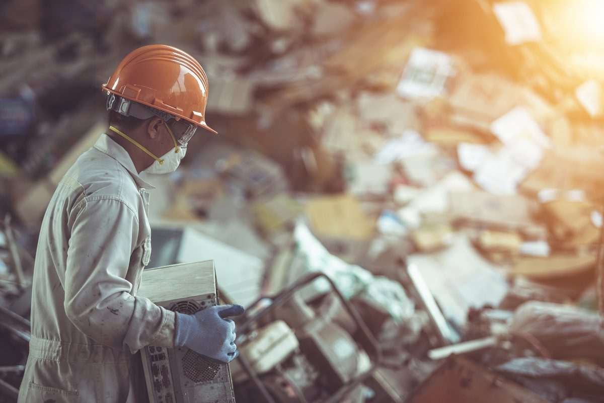 Worker handling discarded electronic equipment at an e-waste recycling facility