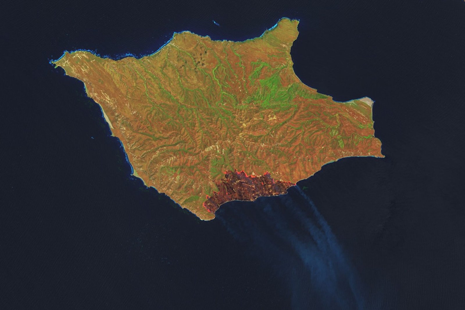 A downward-looking image of Santa Rosa Island shows a dark-brown burned area toward the bottom-right. A thin, bright orange line runs along the burned area, indicating the active fire front.