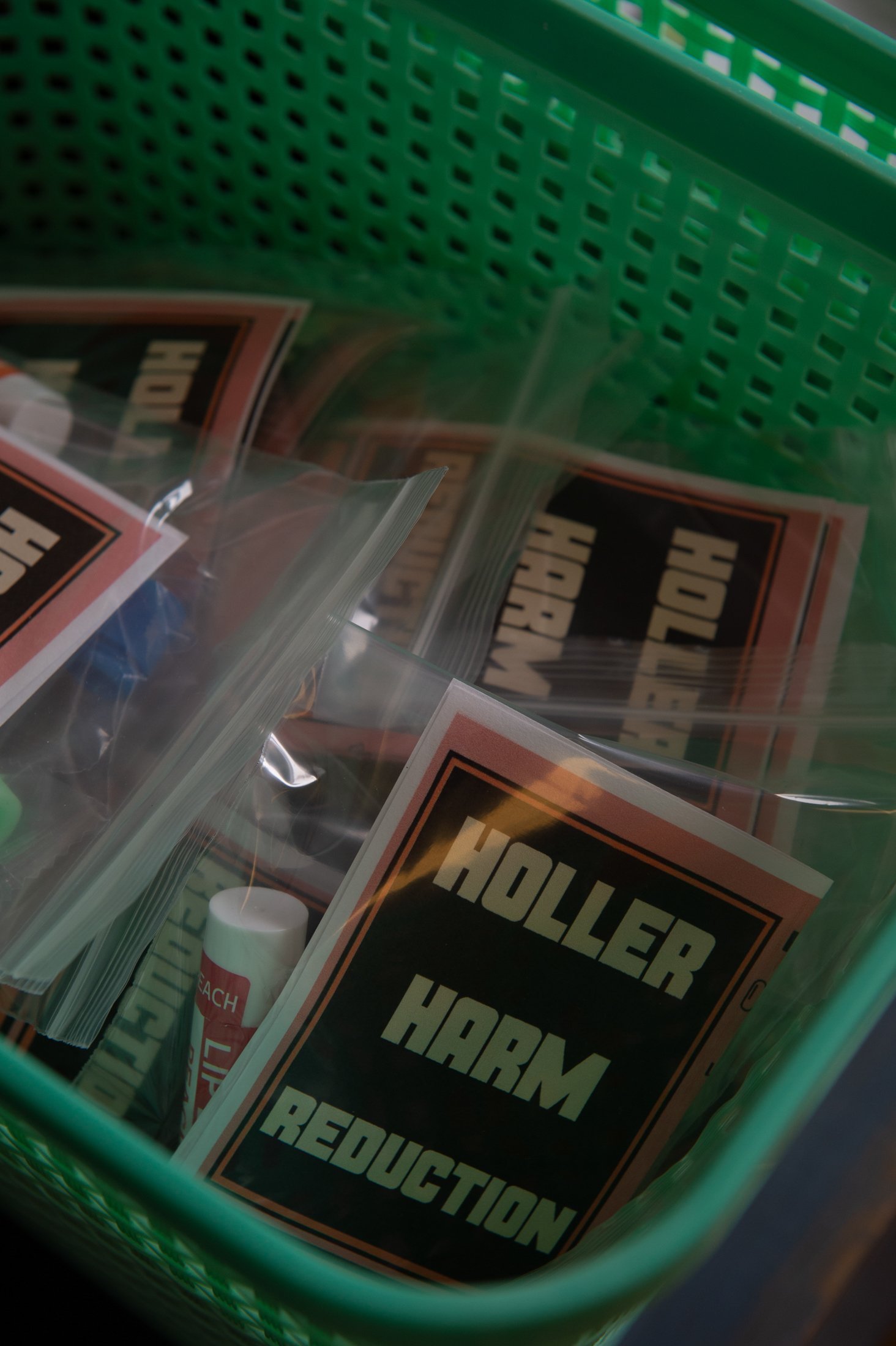 A bin full of plastic bags, which contain lip balm and the logo for Holler Harm Reduction.