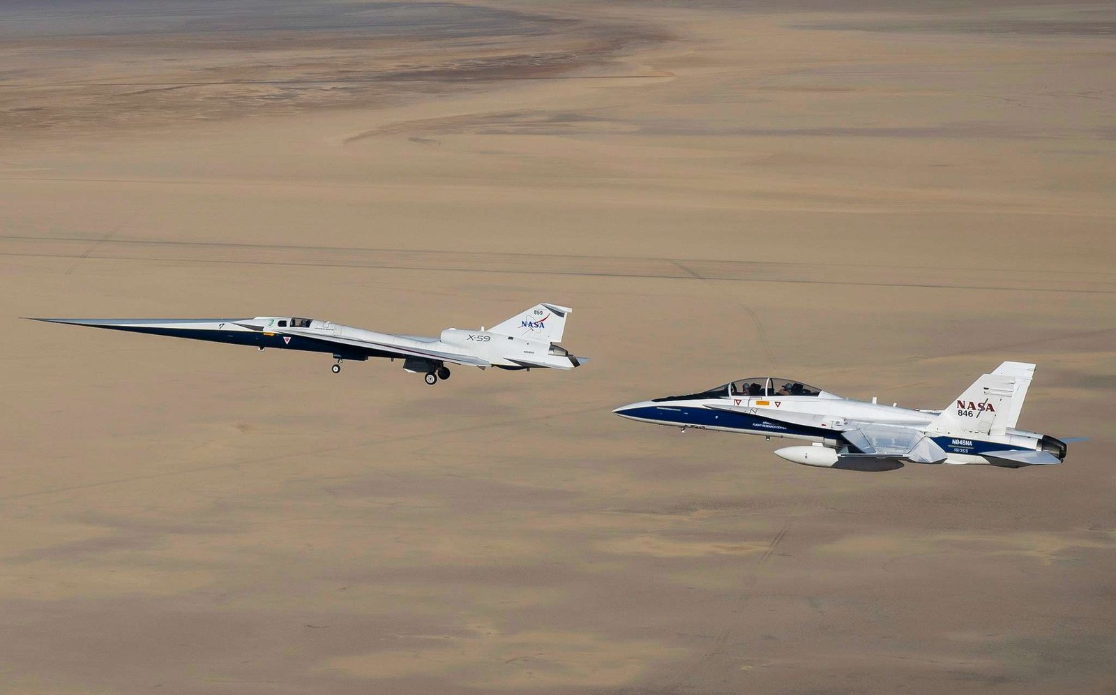 NASA’s X-59 flies above the Mojave Desert with a NASA F/A-18 chase aircraft nearby.