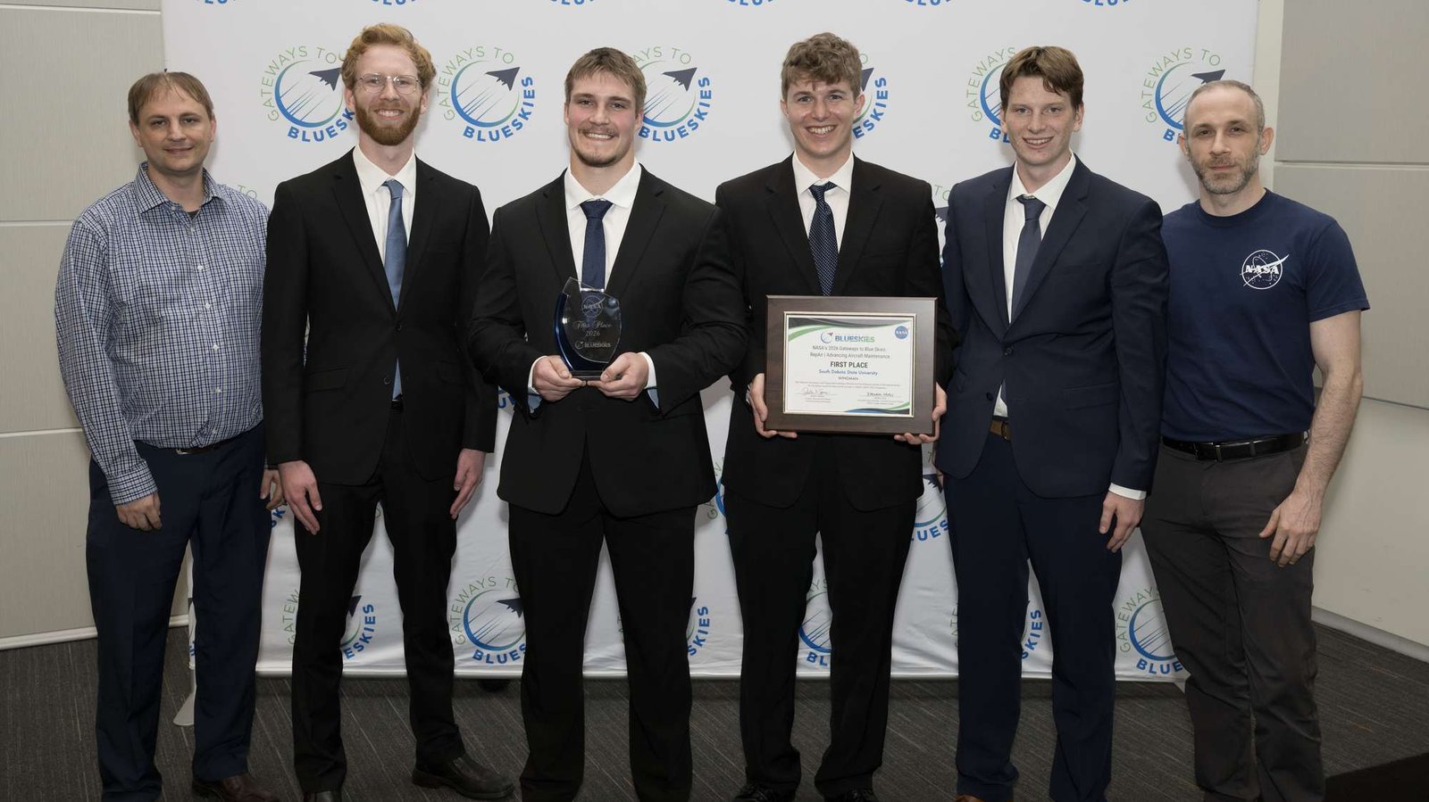 The members of team WINGMAN stand in the center of the photo holding their first place certificate for NASA's Gateways to Blue Skies Competition.