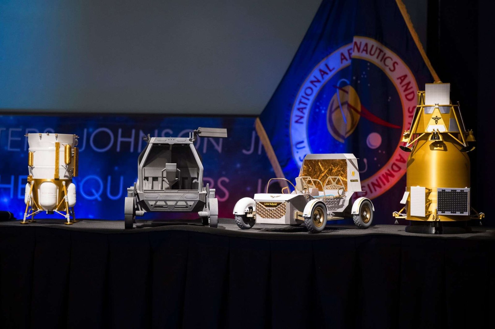 From left to right, models of the Blue Origin Mark 1 Lunar Lander, Astrolab Crewed Lunar Rover, Lunar Outpost Pegasus rover, and the Firely Elytra Dark orbiter are seen at the conclusion of a news conference to discuss Moon Base, a long-term lunar exploration and infrastructure initiative designed to enable sustained human presence and expanded scientific and commercial activity at the lunar South Pole, Tuesday, May 26, 2026, at the Mary W. Jackson NASA Headquarters building in Washington. Photo Credit: (NASA/Aubrey Gemignani)