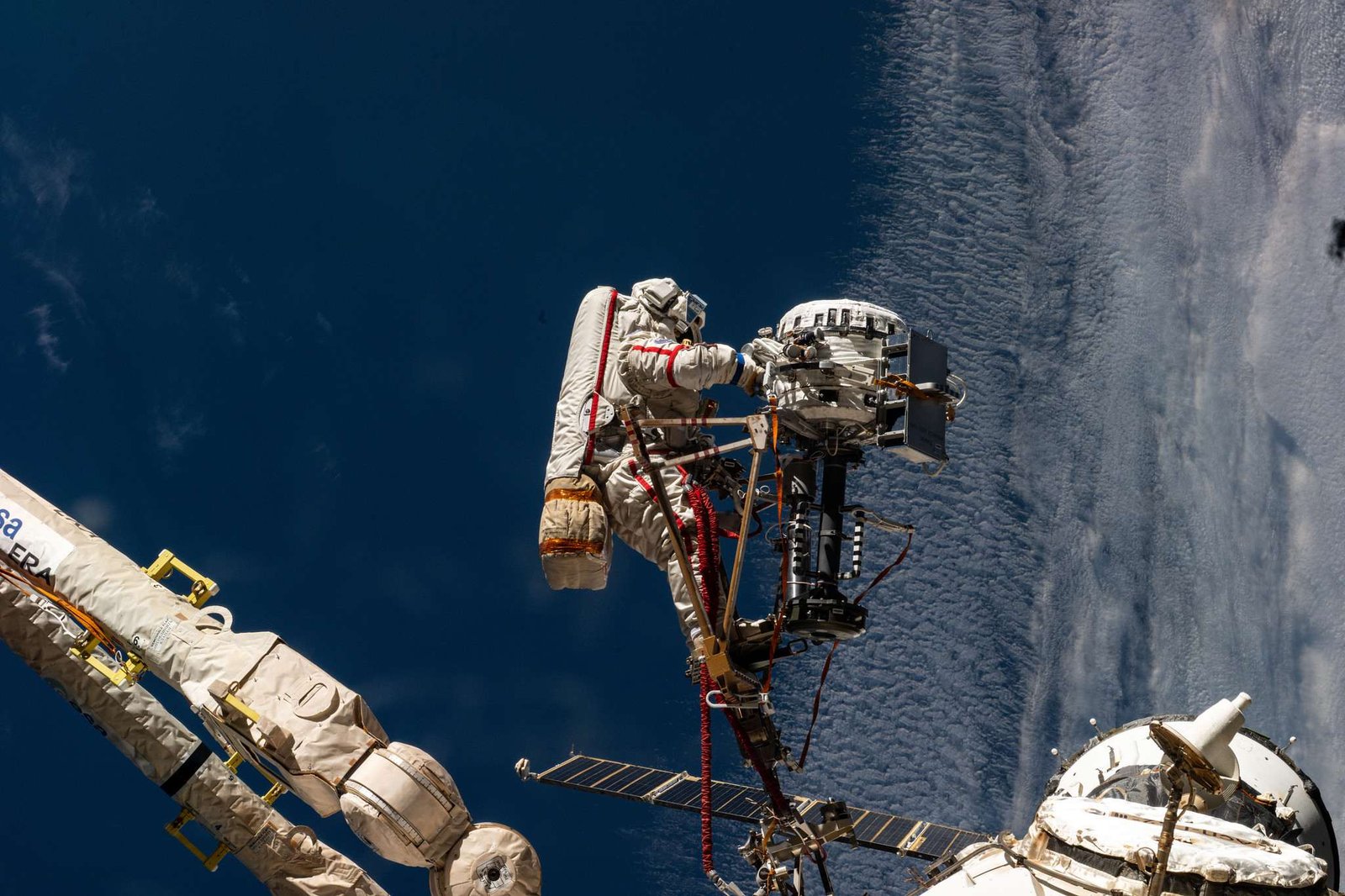 Roscosmos cosmonaut Sergey Ryzhikov is pictured at the end of the European robotic arm as he works on a high‑resolution camera during a six‑hour, nine‑minute spacewalk outside the International Space Station on Oct. 16, 2025