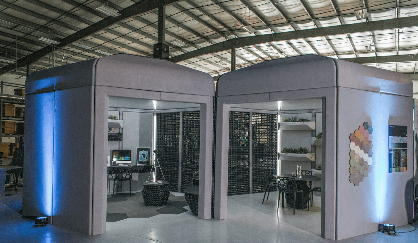 Two boxy structures, one with an office-like interior and the other with an eating area, side-by-side in a hangar-like location