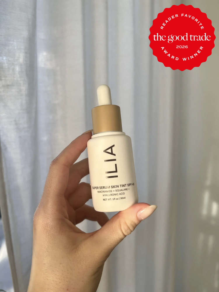 A hand holds a bottle of ILIA Super Serum Skin Tint SPF 40 against a neutral background. A red badge in the corner reads "The Good Trade Reader Favorite Award Winner 2026.