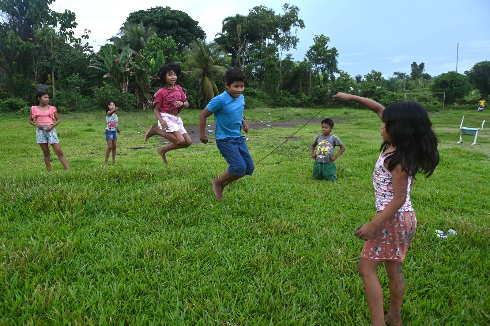 Children play jump rope in a field