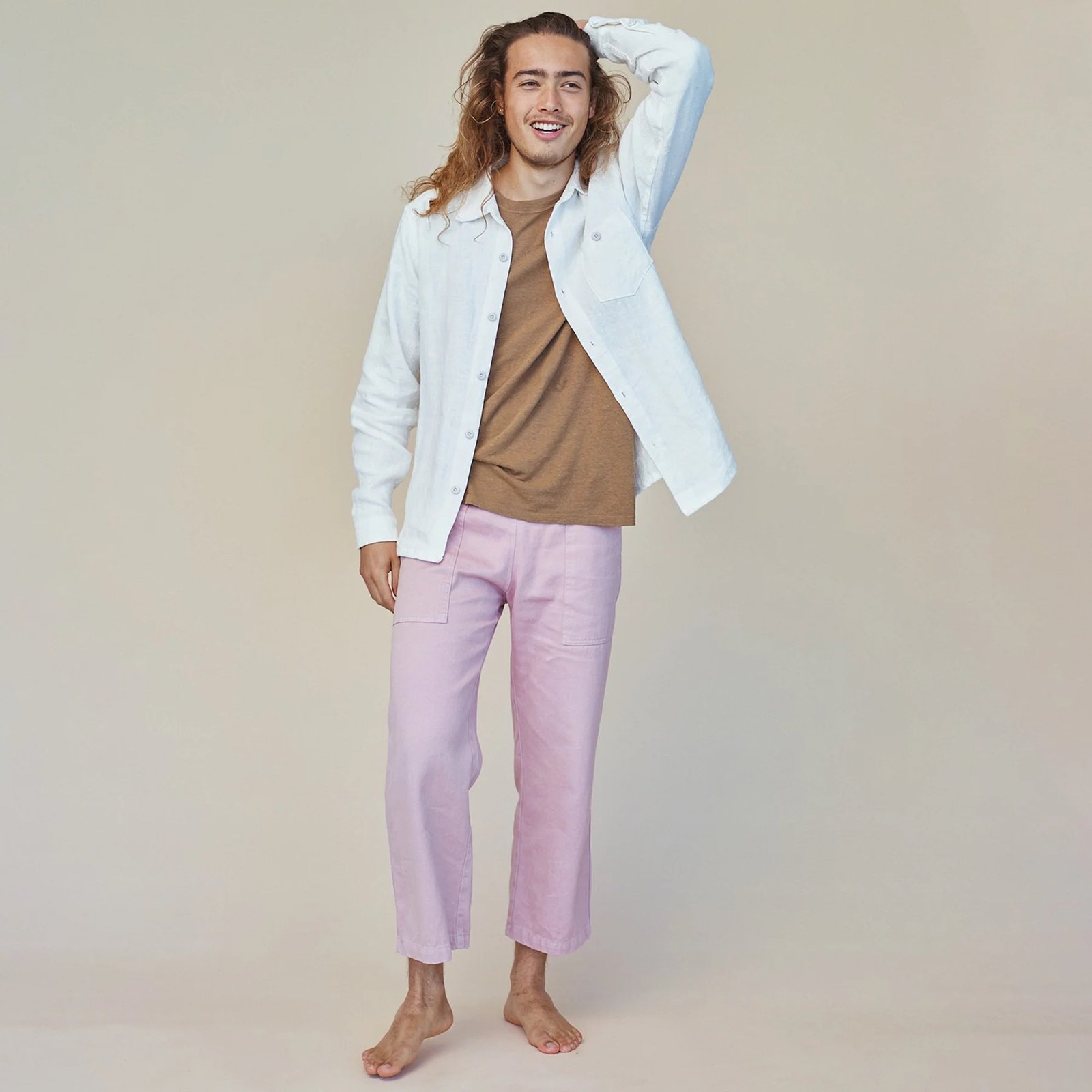 A model wearing Jungmaven lavender hemp pants runs his hand through his hair. 