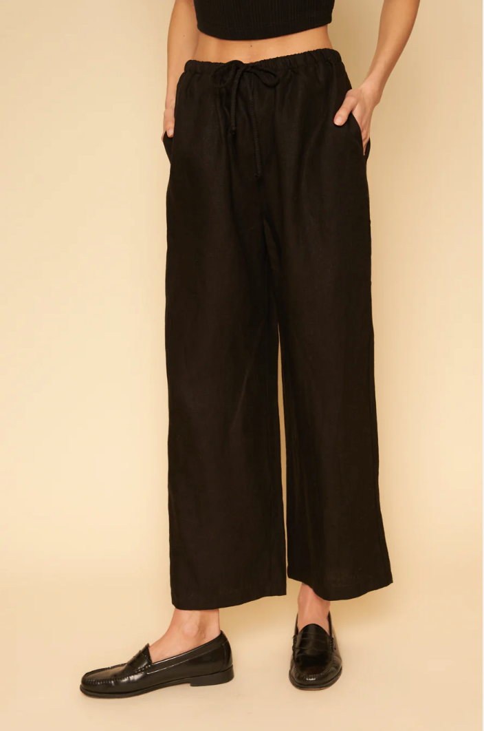 A model's legs in loose black linen pants. 