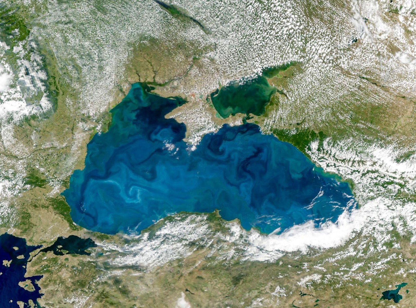 A satellite image shows swirling turquoise water in the Black Sea, centered within the frame.
