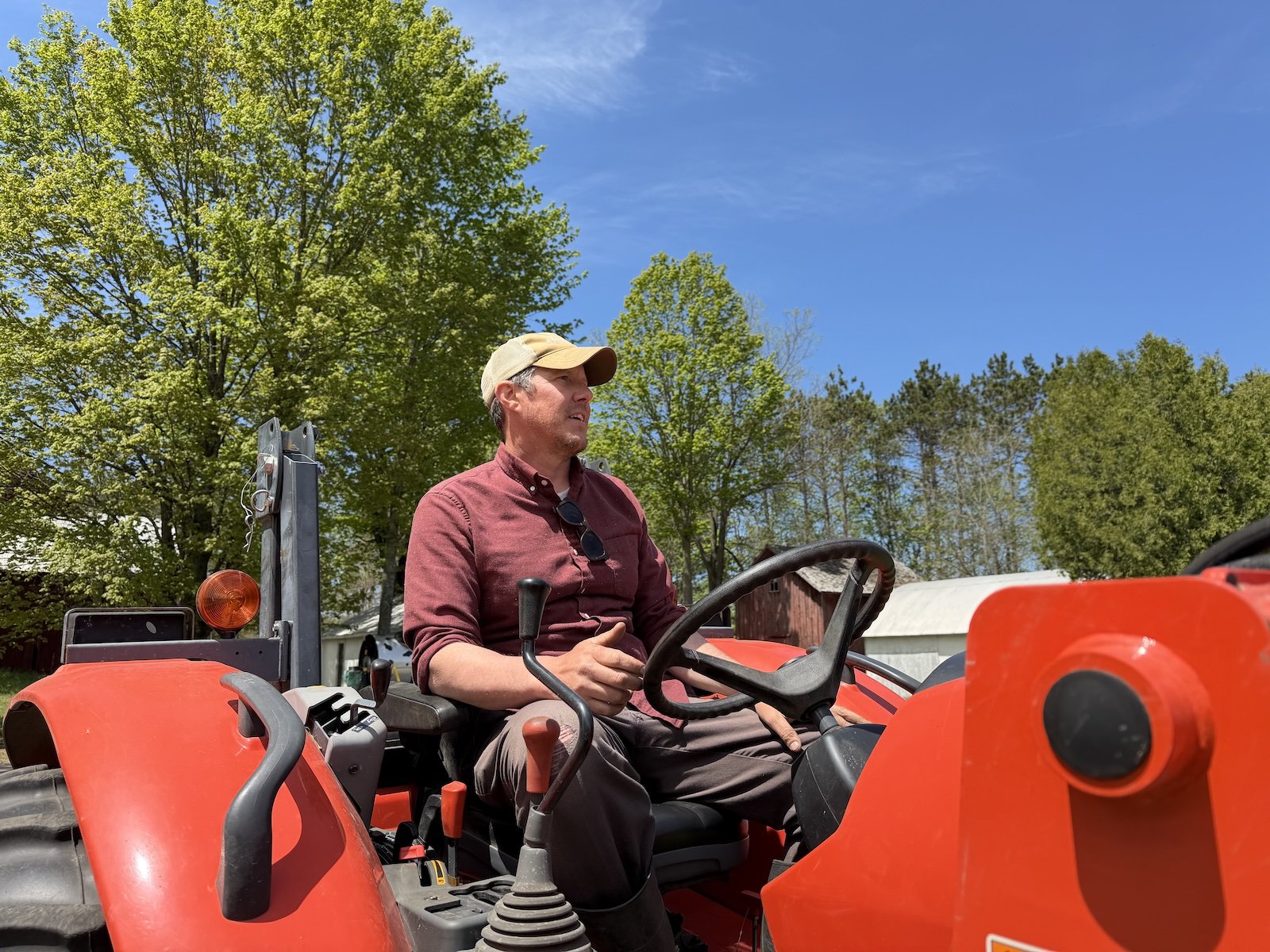 A man sits on a red tractor outdoors