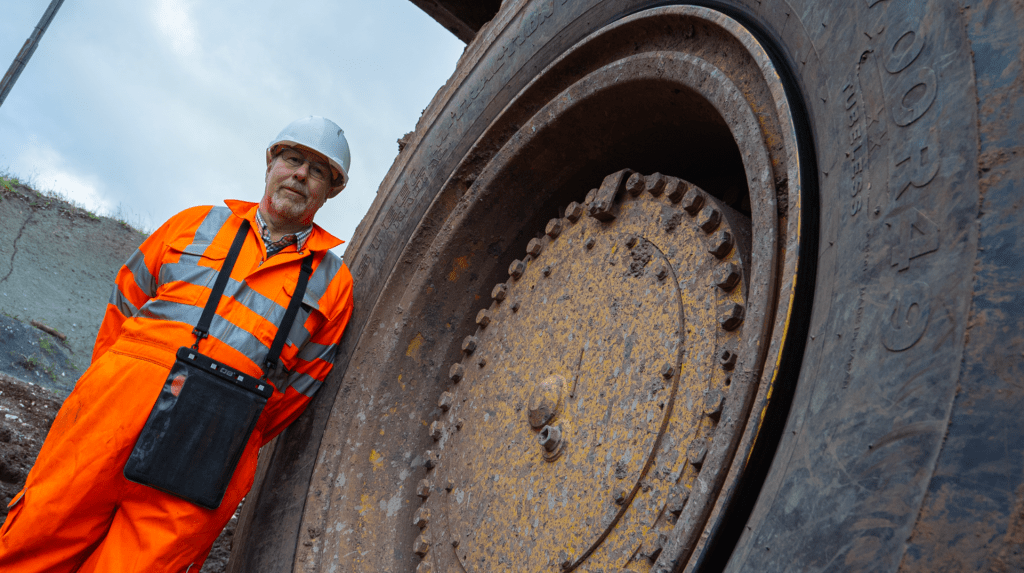 Bridgestone’s Rob Cole, key account manager – off-road tires, UK and Ireland, stands in front of a Bridgestone mining tire on a large off-road machine.