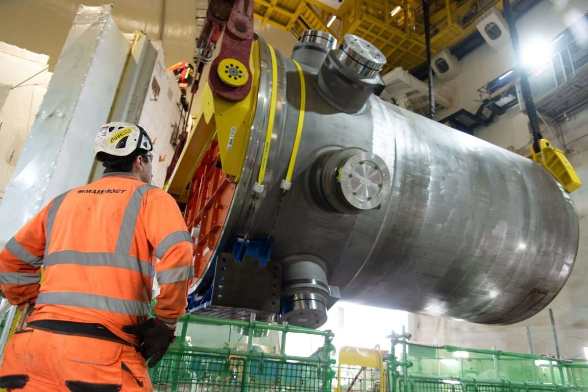Engineer watches as a large stainless-steel reactor pressure vessel is manoeuvred into position by the polar crane inside Hinkley Point C's Unit 2 reactor building in Somerset