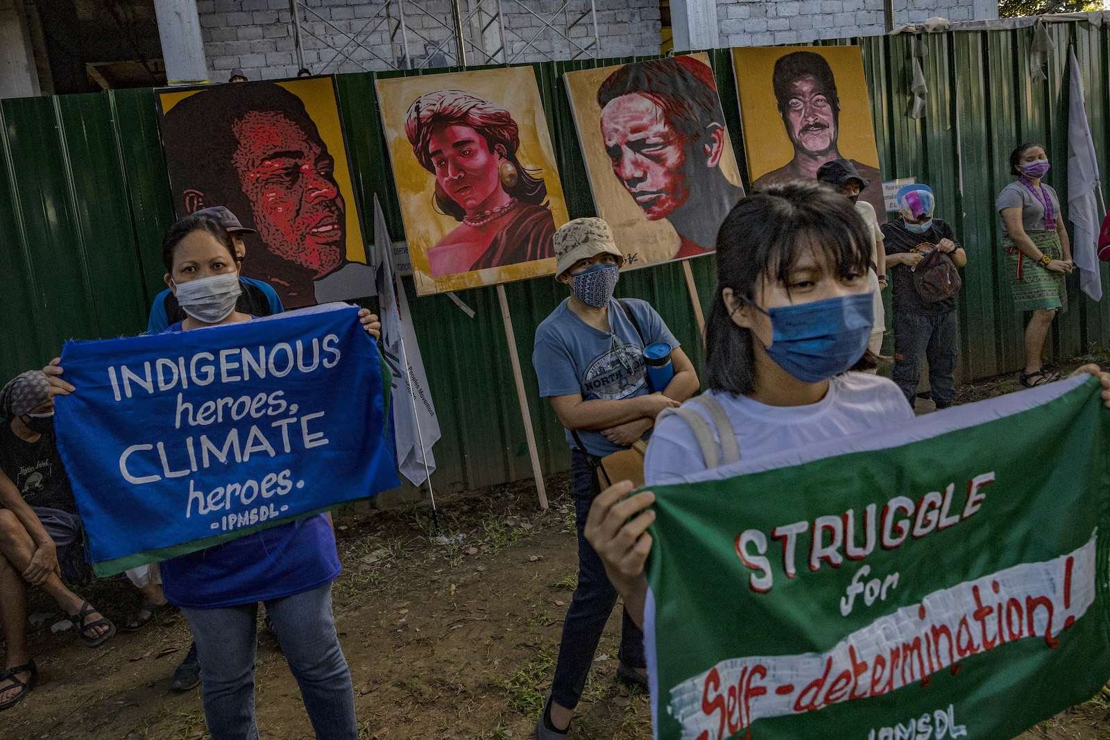 A group of climate protesters carry signs and portraits of Indigenous land defenders