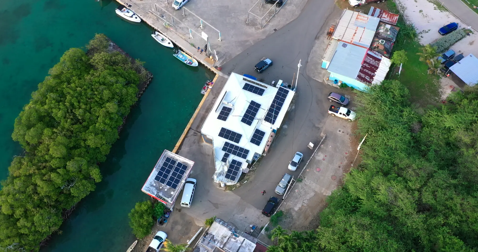 An aerial view of a building near docks. The building has solar panels on top.