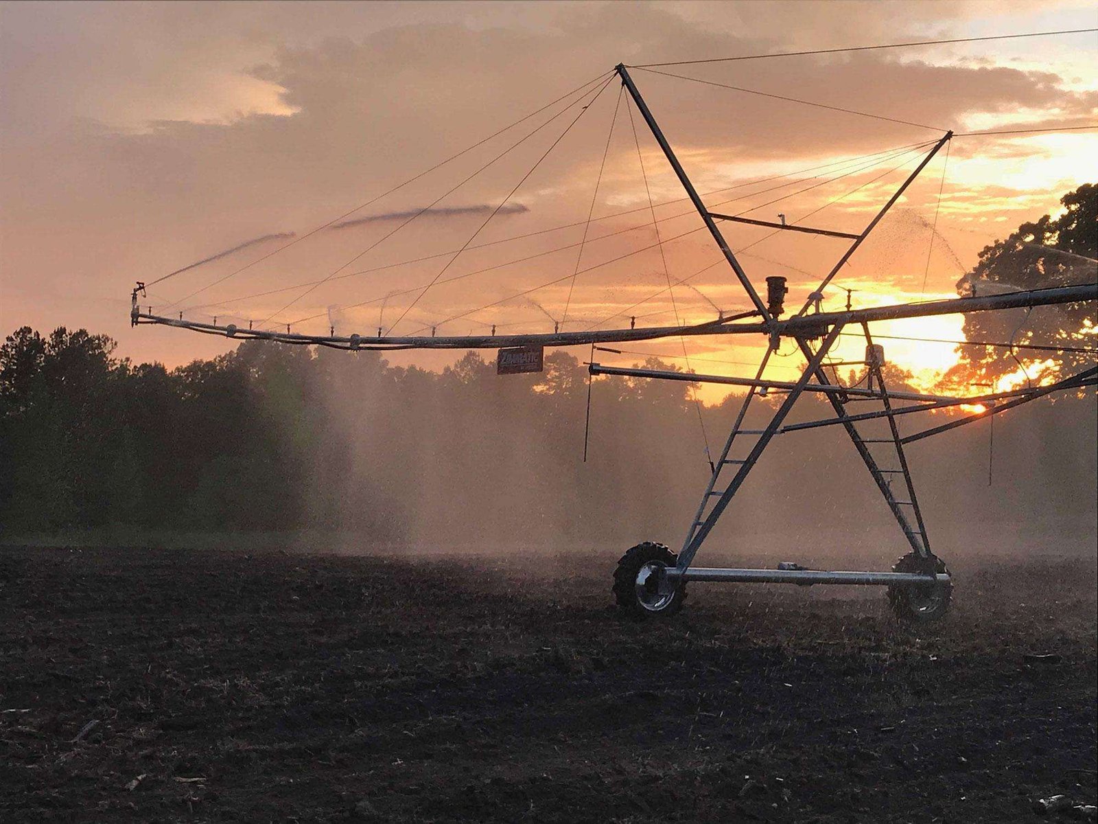 irrigation equipment watering a field with a sunset in the background