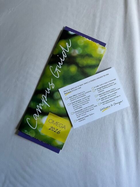 A campus guide brochure labeled "Omega 2026" and an orientation checklist card are placed on a white surface.