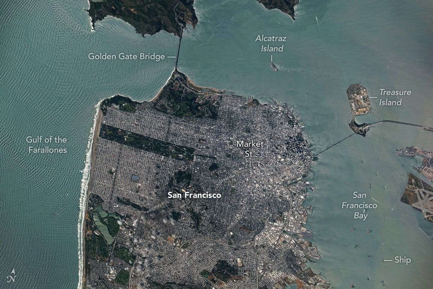 A top-down photo of San Francisco shows dense gray urban infrastructure interspersed with green parks. Waves and ships are visible in the surrounding blue-green water.