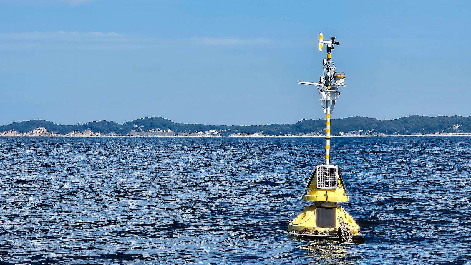 Floating yellow weather station buoy on blue Lake Michigan.