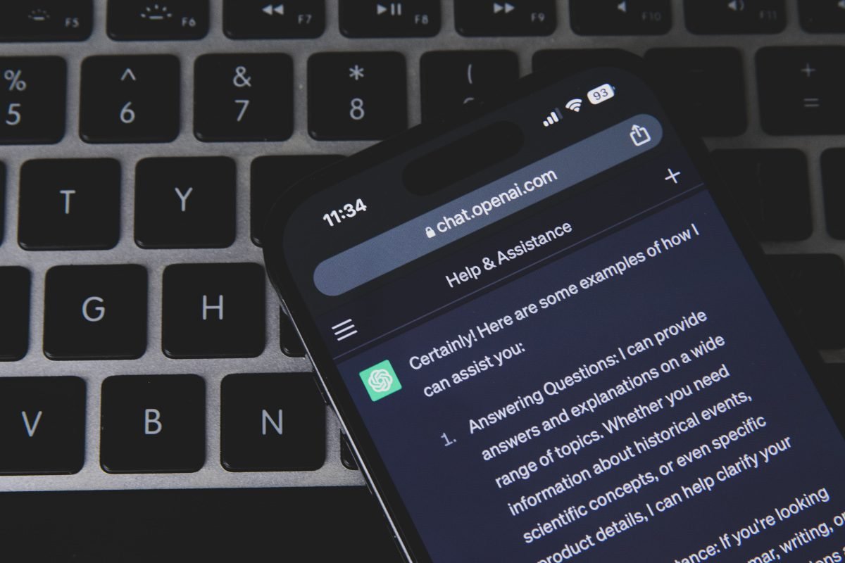 The ChatGPT AI platform prompt visible on a smartphone screen, with a desktop computer keyboard partly visible in background