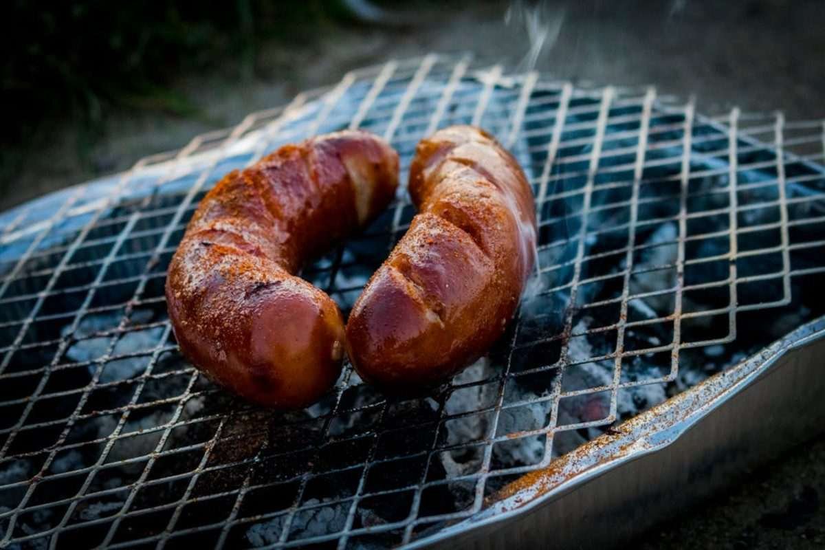 Sausages cooking on the grille of a disposable bbq
