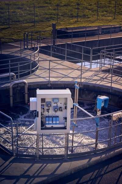 Water treatment monitoring equipment installed beside a circular settlement tank at a wastewater treatment plant