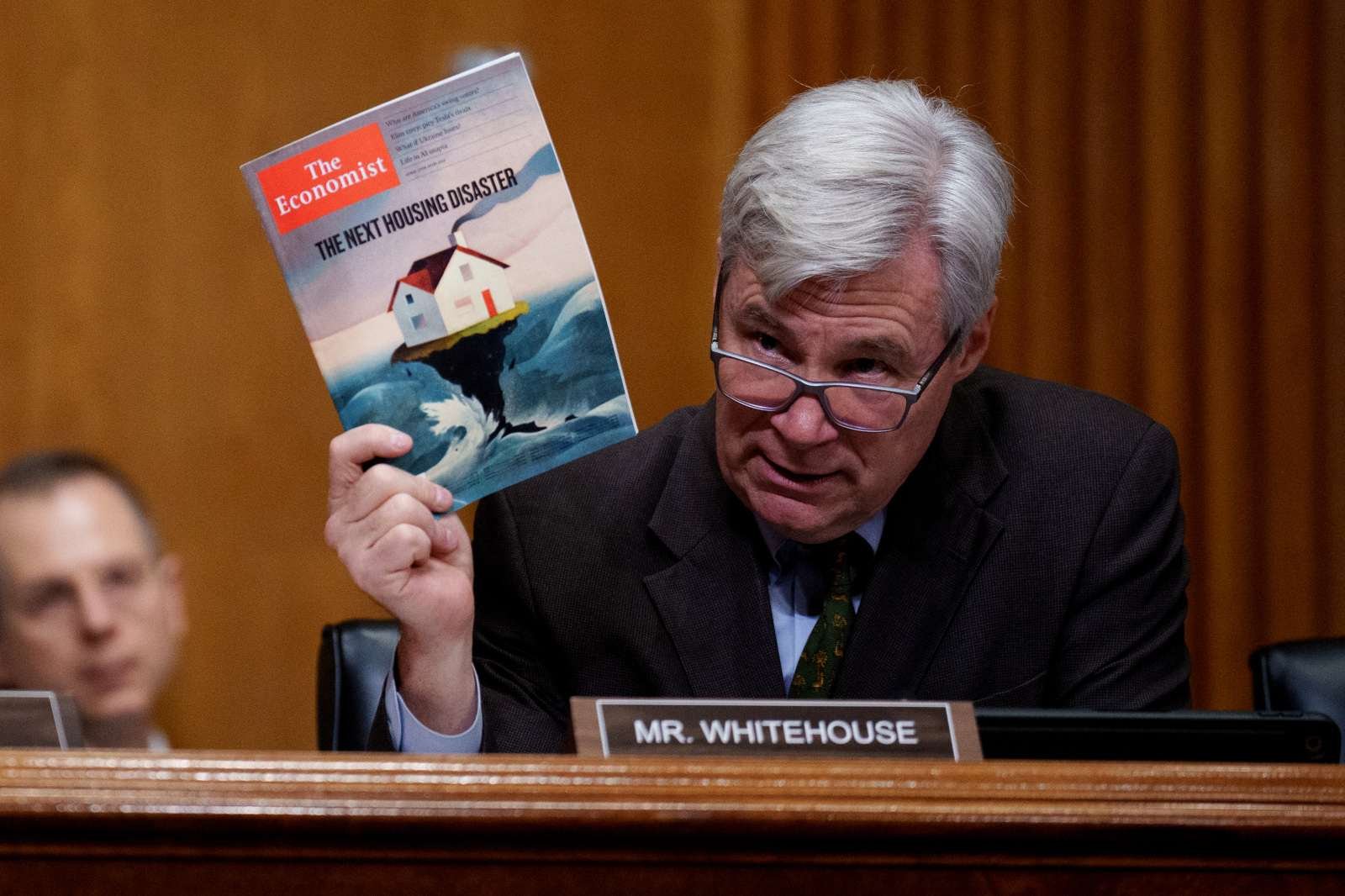 Photo of Senator Whitehouse holding up an economist magazine with the headline "the next housing disaster"