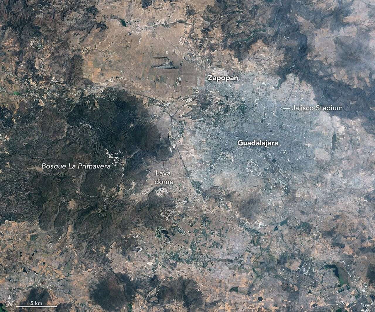 : Images of Guadalajara in 1986 (left) and 2026 (right) shows the city expanding westward into an area that had been mostly farmland. Guadalajara Stadium appears as a small circular feature on the left side of the 2026 image.