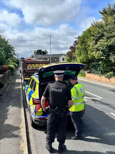 Police and Driver and Vehicle Standards Agency (DVSA) officers inspect a waste-carrying vehicle during a roadside enforcement operation targeting suspected illegal waste transport in Lancashire