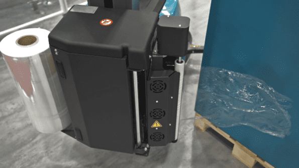 A packaging machine with a roll of film loaded beside a pallet wrapped in plastic.