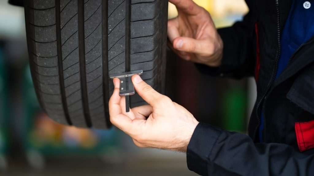 A man runs a piece of testing equipment along the side of a tire.