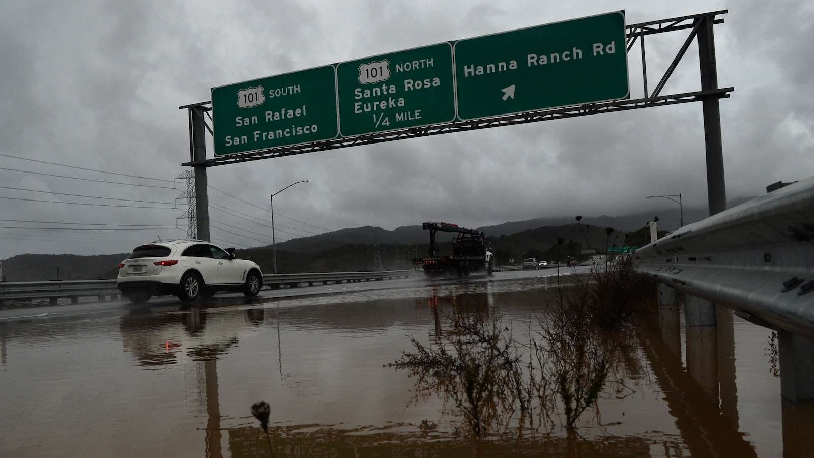 Traffic splashes through a flooded California Highway 37.
