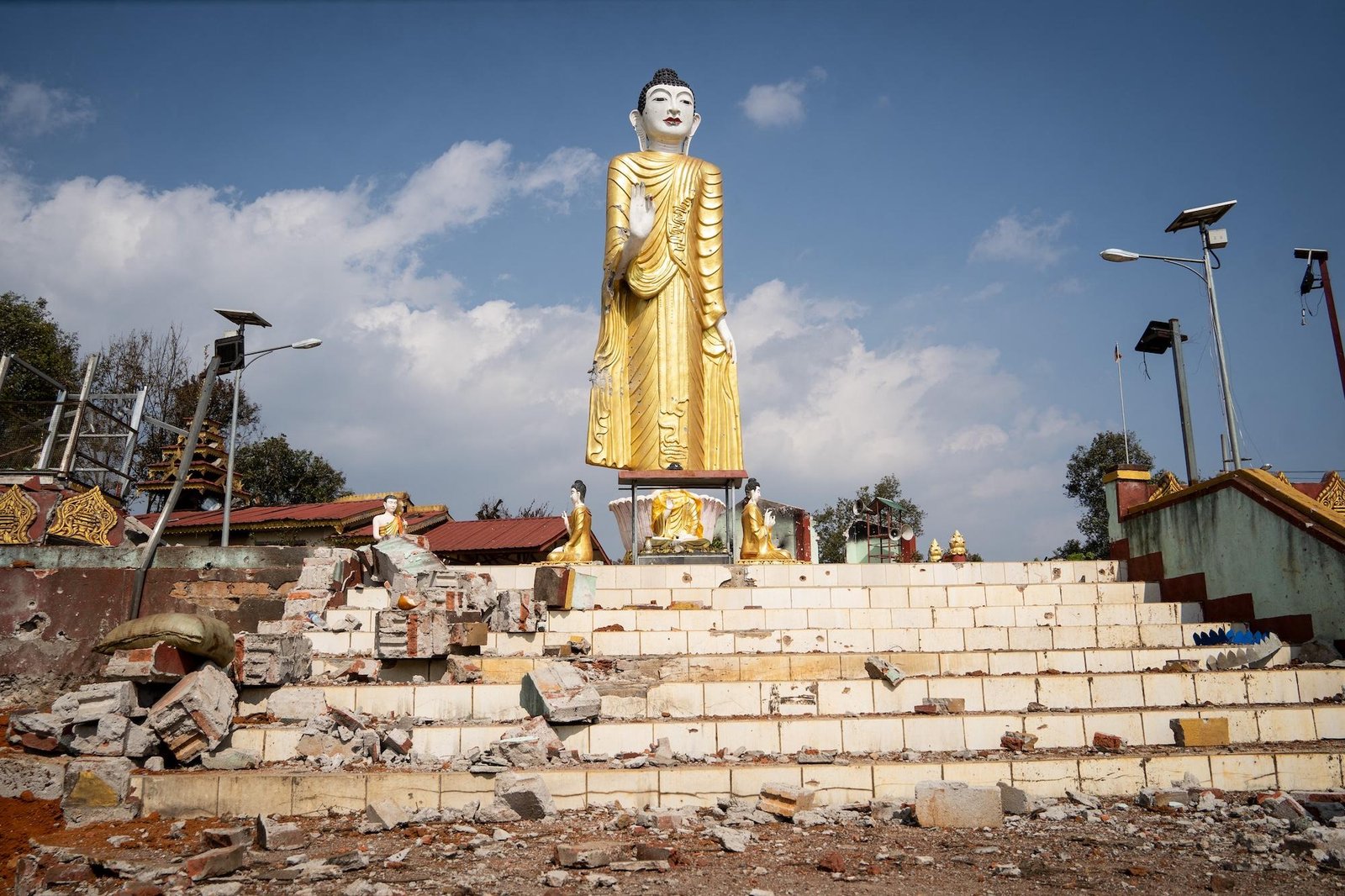 bombing debris surround a statue of Buddha