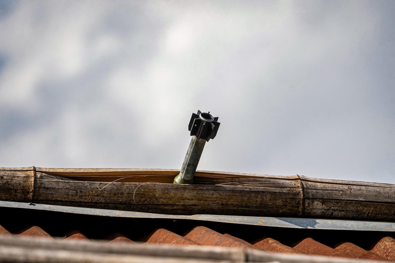 An unexploded projectile sticks out of a piece of roofing