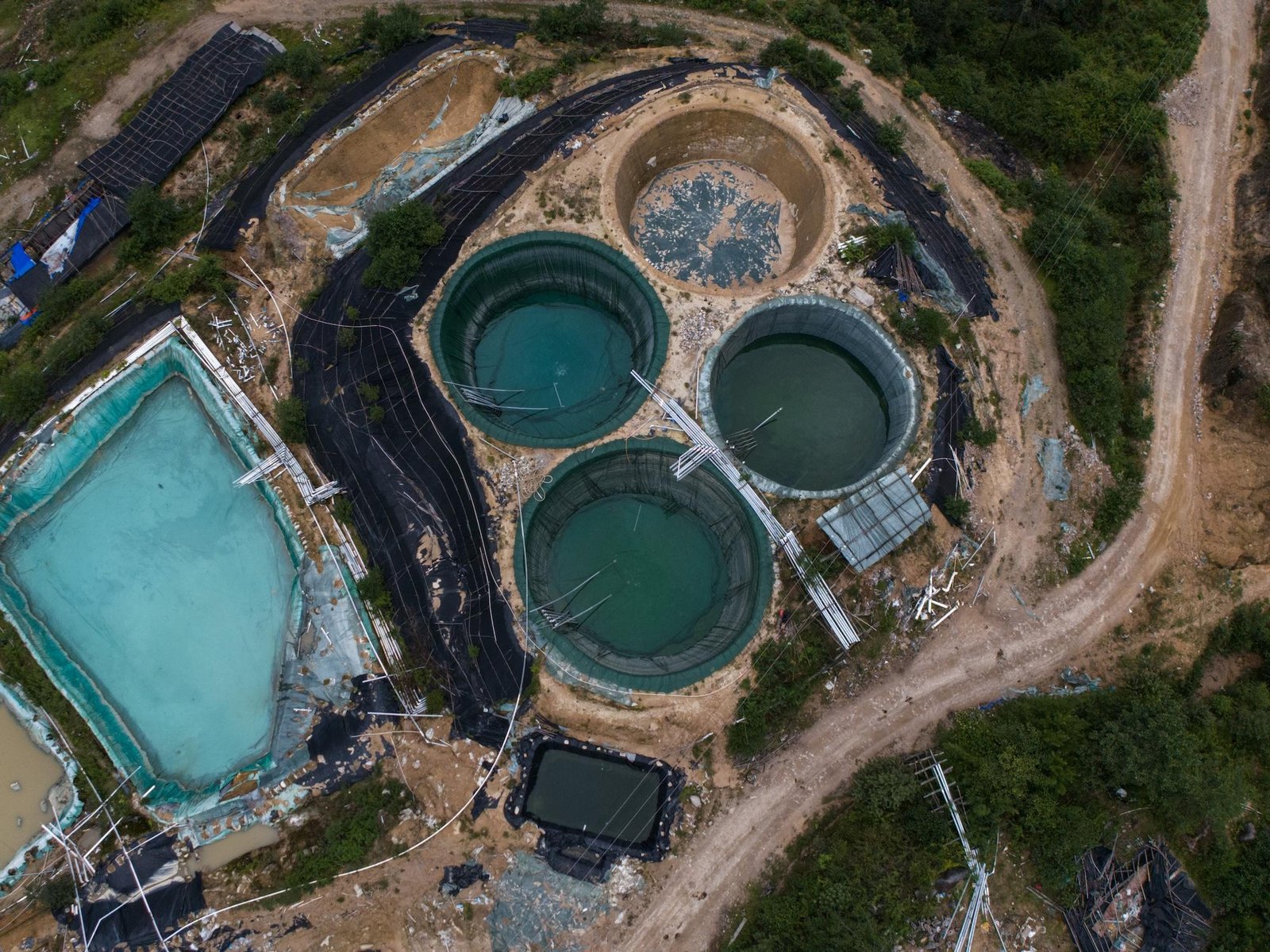 an aerial shot of a rare earth mining site including round structures and liners