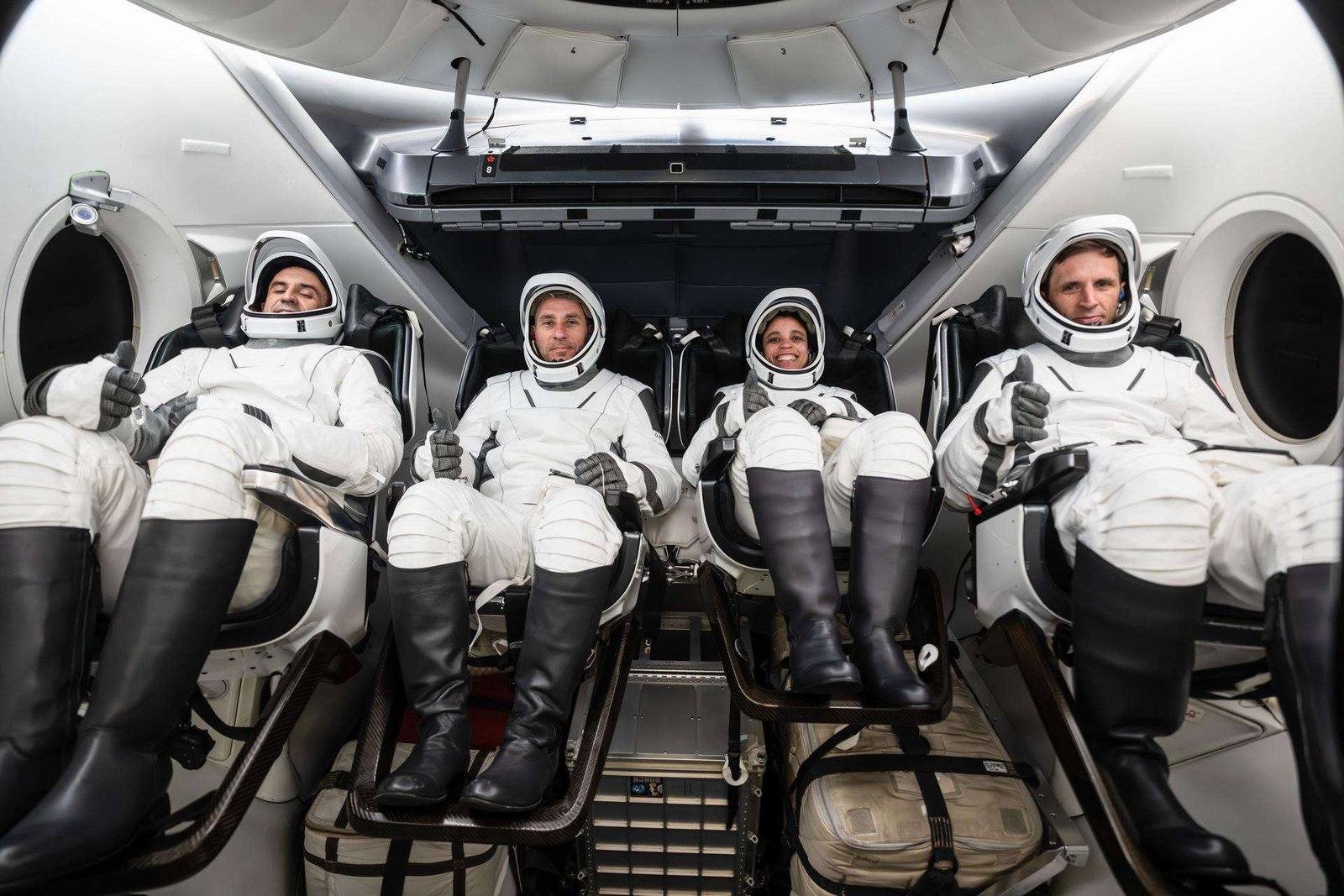 The SpaceX Crew-13 members are pictured in their pressure suits seated inside a mockup Dragon spacecraft during a preflight training session at the company's headquarters in Hawthorne, California. From left are, Roscosmos Sergey Teteryatnikov, NASA astronauts Luke Delaney and Jessica Watkins, and CSA (Canadian Space Agency) astronaut Joshua Kutryk.