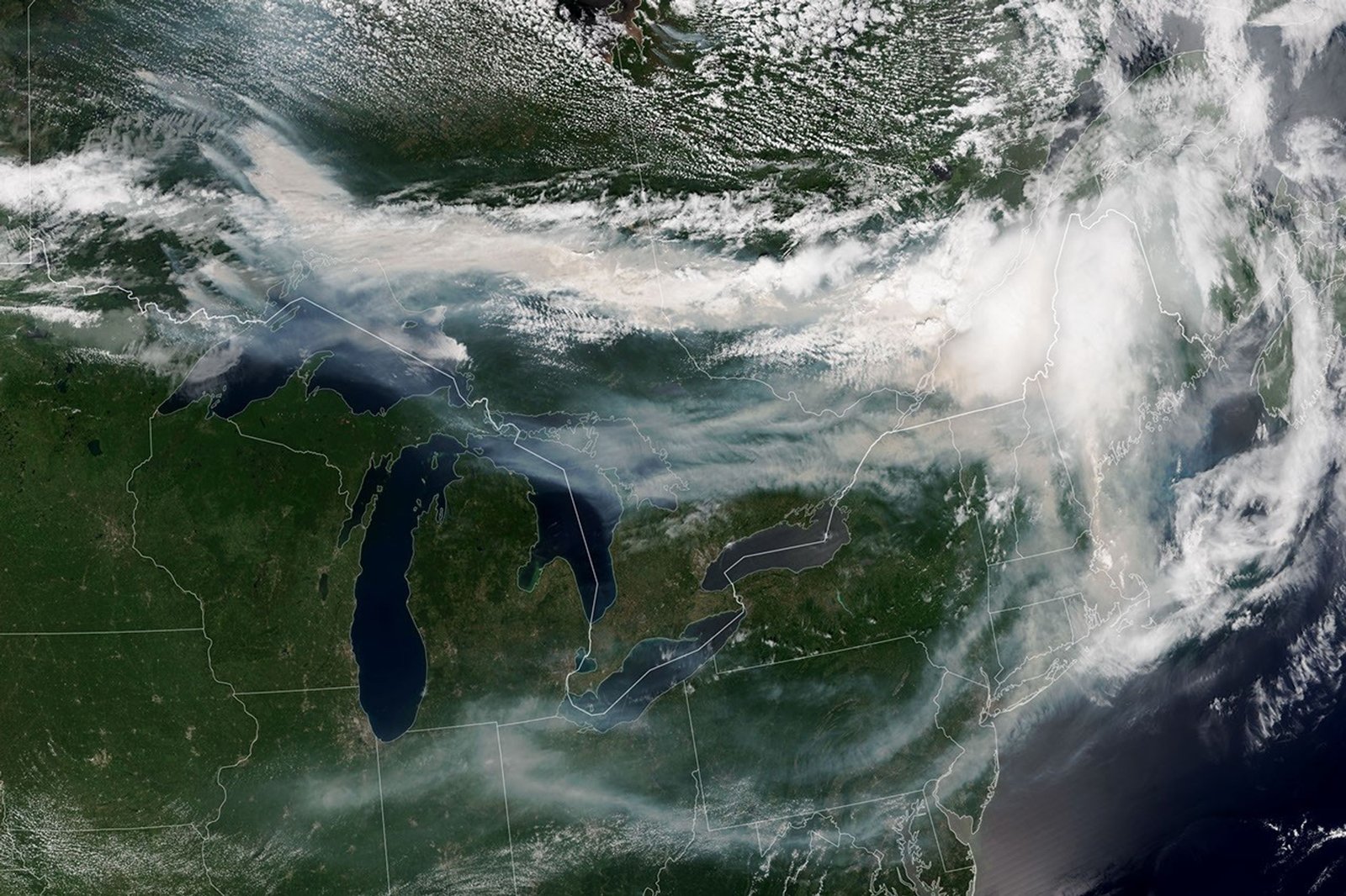 A satellite image shows brown smoke from wildfires in Ontario, Canada, streaming east across parts of Canada and the U.S. Areas of white clouds are mixed in with the smoke.