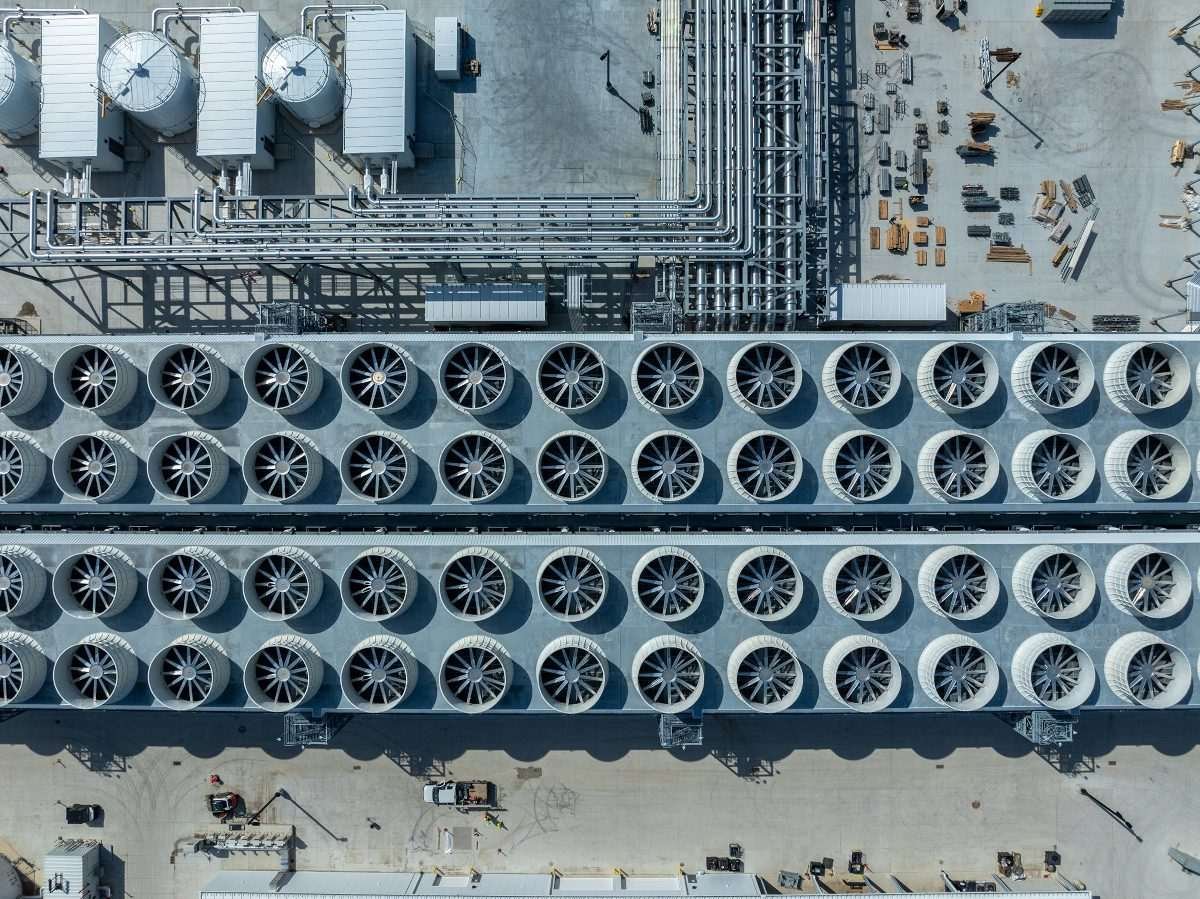 Top-down aerial of an AI data center with extensive cooling fans, piping, and infrastructure