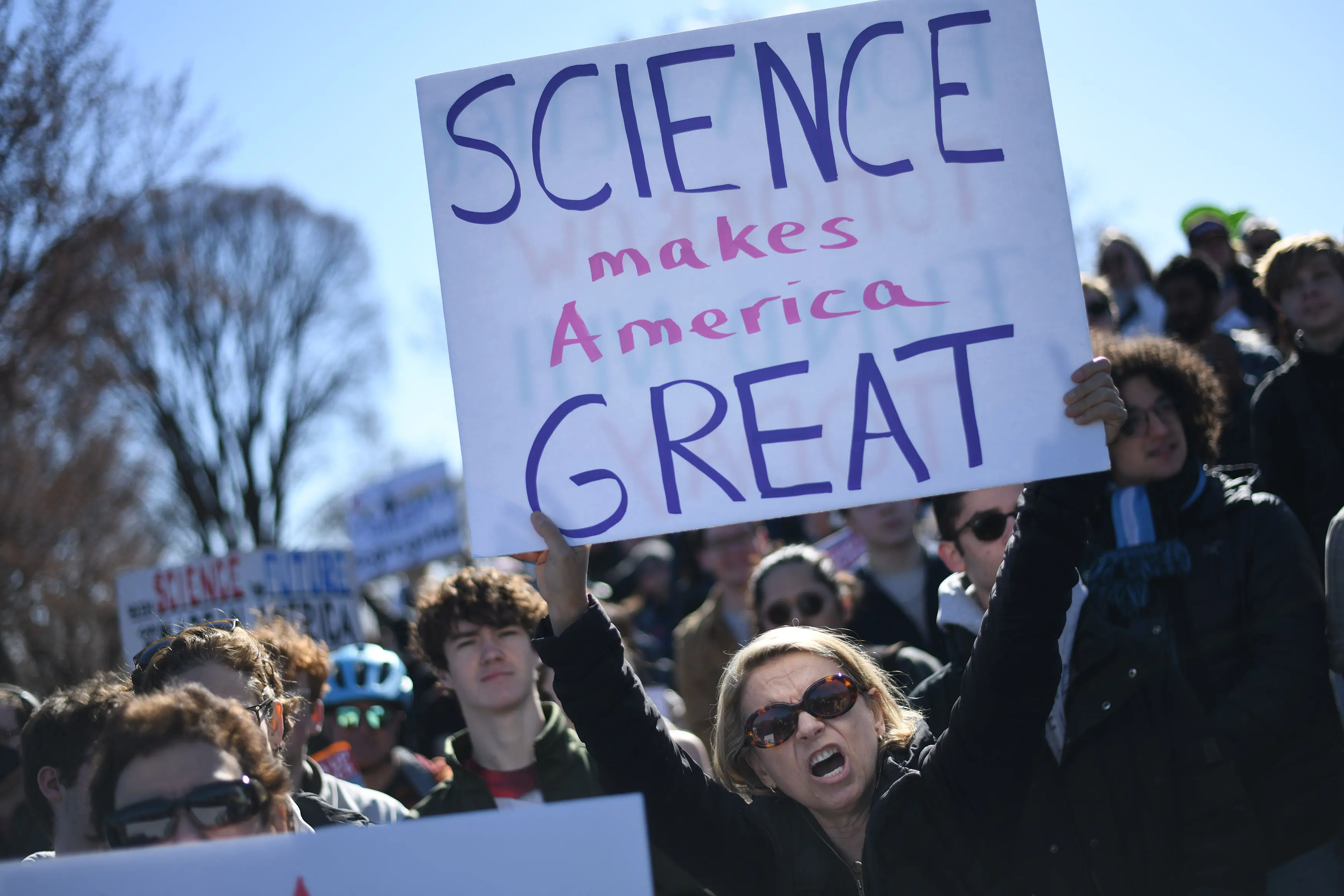 A woman holds a protest sign that says 'science makes america great'