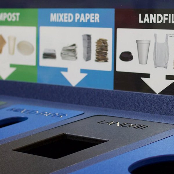 A trash and recycling bin with restricted openings and clear signage for correct waste management