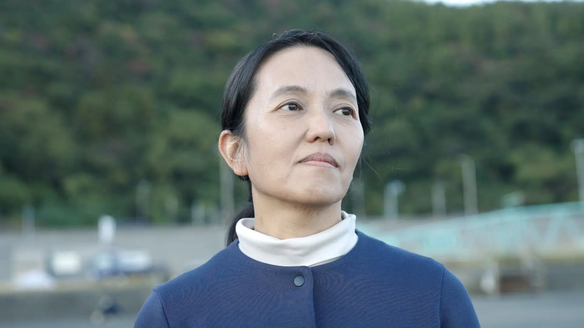 a japanese woman stands near the ocean