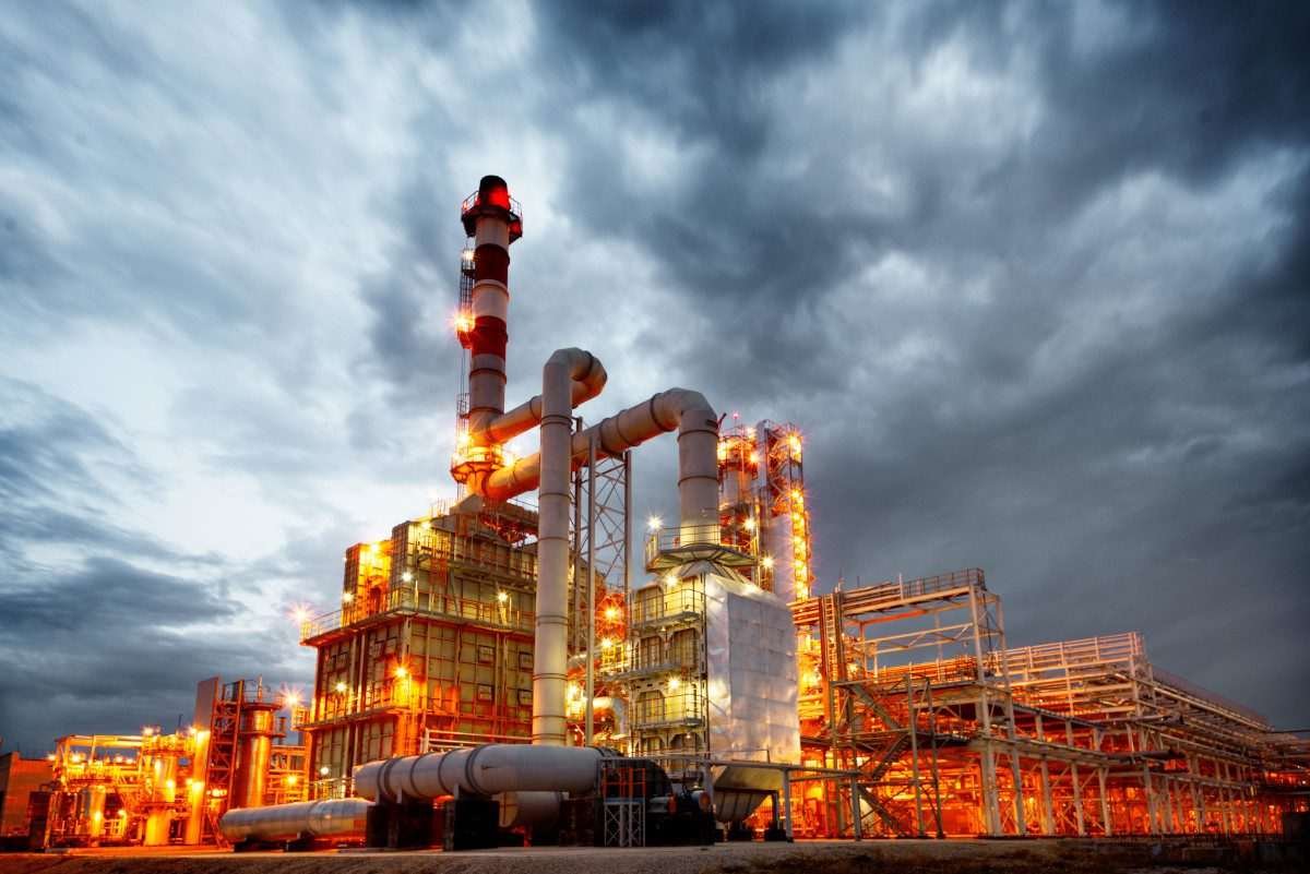 Oil and gas plant seen from ground level, and against a clouded sky