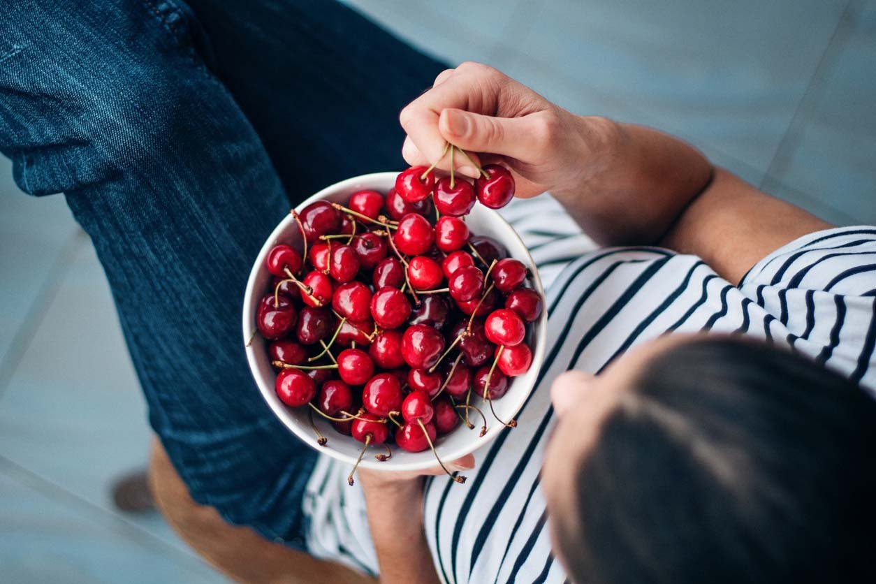 Woman enjoying a bowl full of cherries for her health