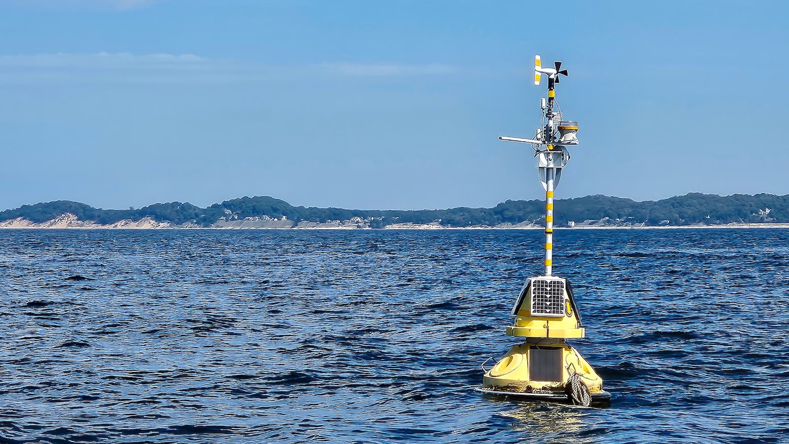Floating yellow weather station buoy on blue Lake Michigan.