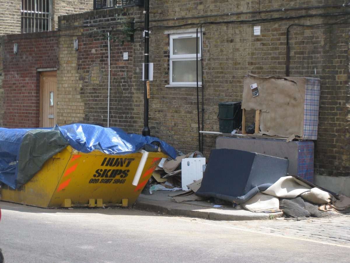 Fly-tipping in yard with residential houses in the background